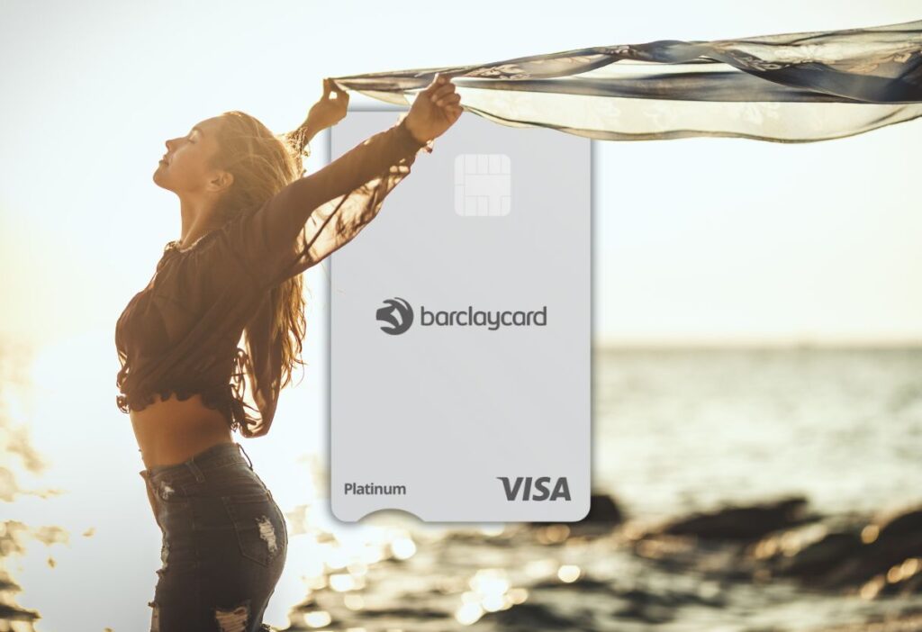 A woman standing by the sea with her arms outstretched, holding a scarf in the wind, with the Barclaycard Platinum Balance Transfer No Fee Card visible in the background.