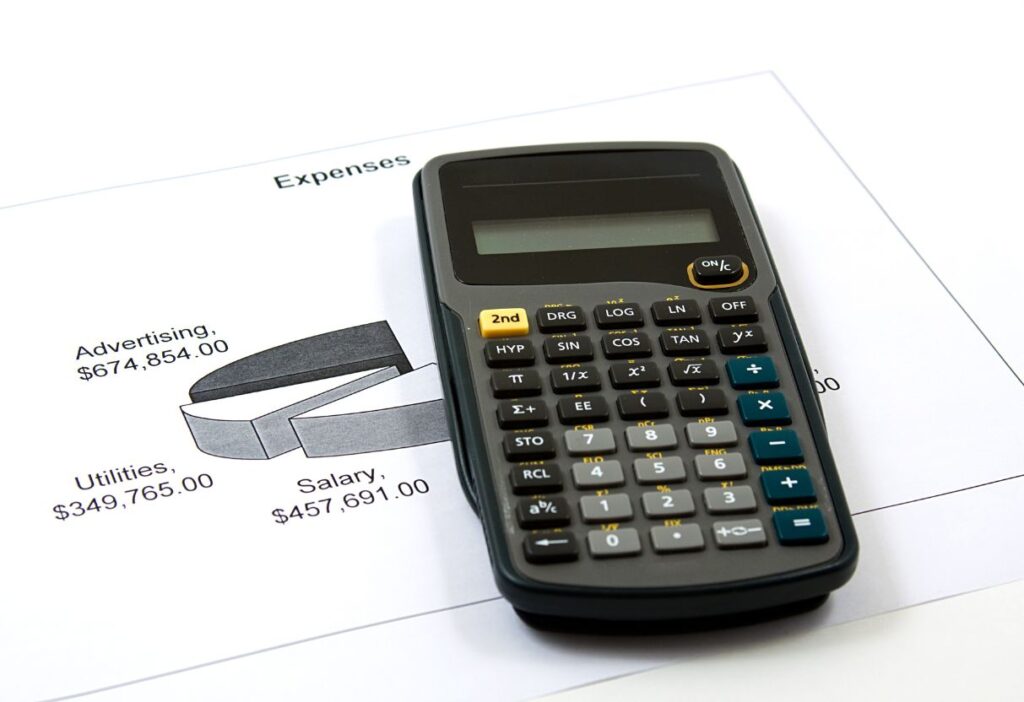 A calculator placed on top of a pie chart showing various expenses, symbolising budgeting and debt management strategies.