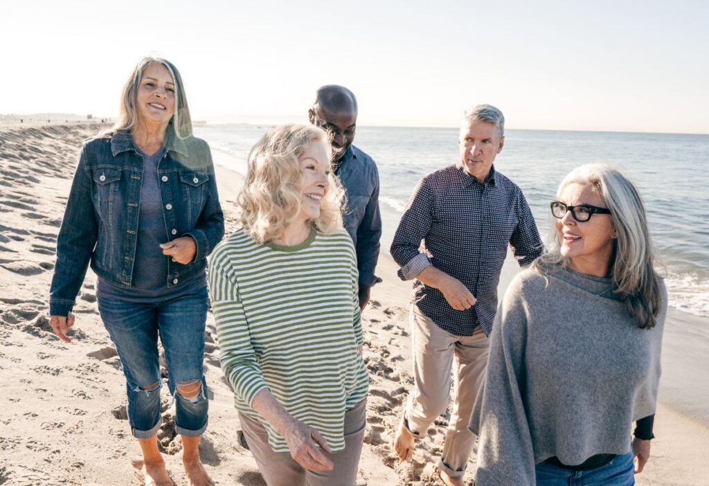 A group of friends enjoying a walk on the beach, symbolising a secure and enjoyable retirement thanks to life insurance.