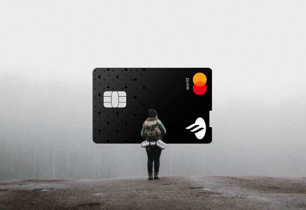 A hiker standing on a foggy landscape, carrying a backpack, with an oversized Santander Edge Credit Card in the background, symbolising adventure and financial freedom.