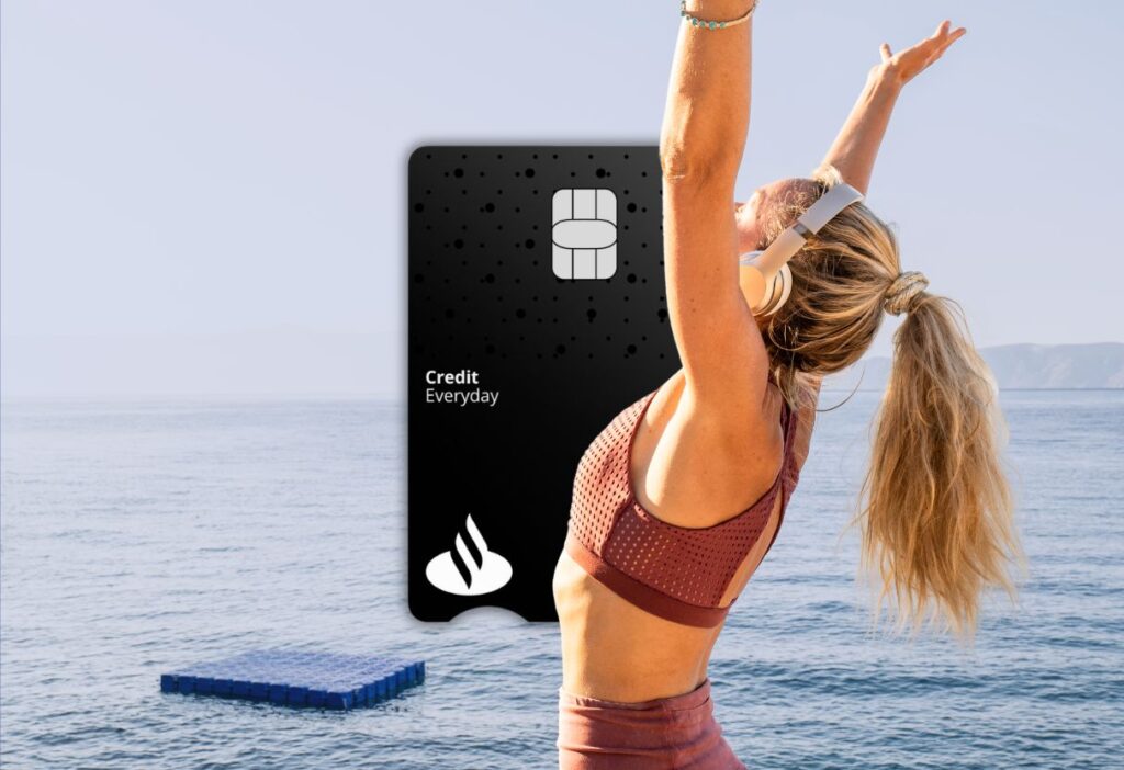 Happy woman stretching by the sea with the Santander Everyday Long Term Balance Transfer Credit Card in the background, representing freedom and control over finances.