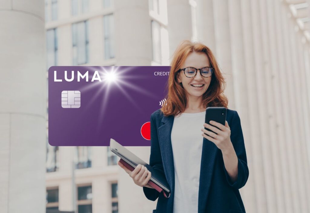 Smiling woman in business attire holding a phone and tablet with a purple Luma credit card overlay, symbolising smart financial management and convenience on the go.